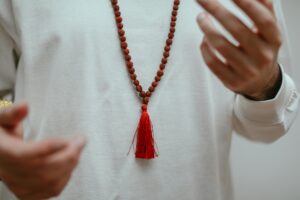 Person in White Long Sleeve Shirt Wearing Rudraksha Mala Necklace